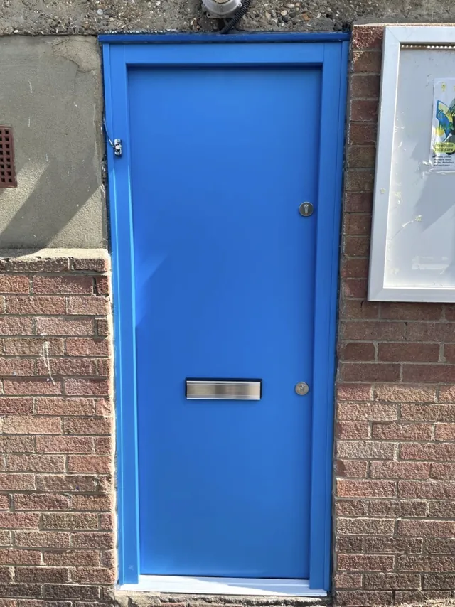 Bright blue entrance door with a letterplate set within an exterior opening