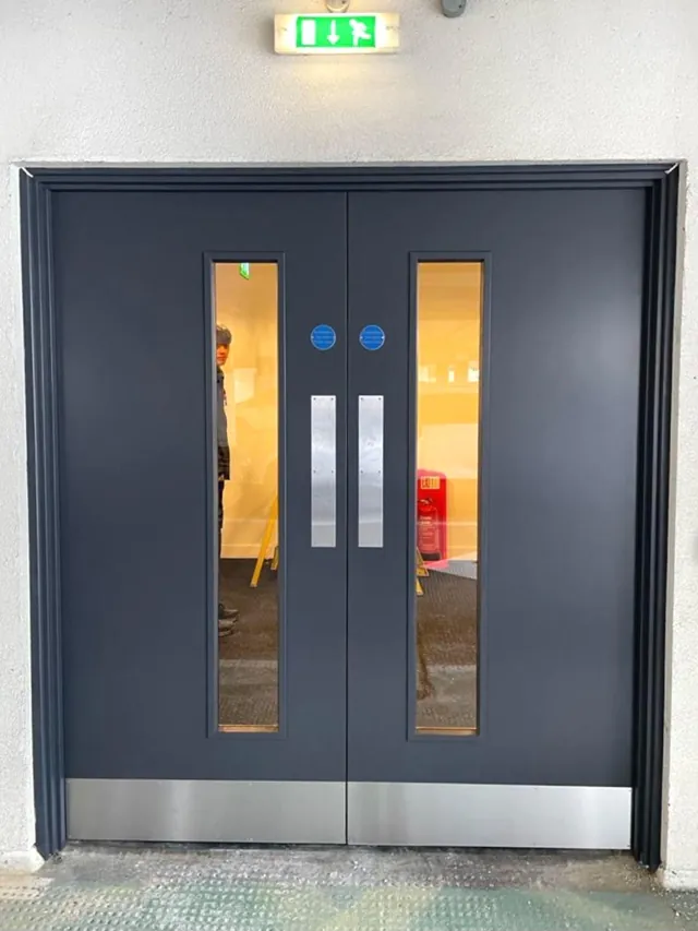 Charcoal double doors with narrow vision panels and lower metal protection plates