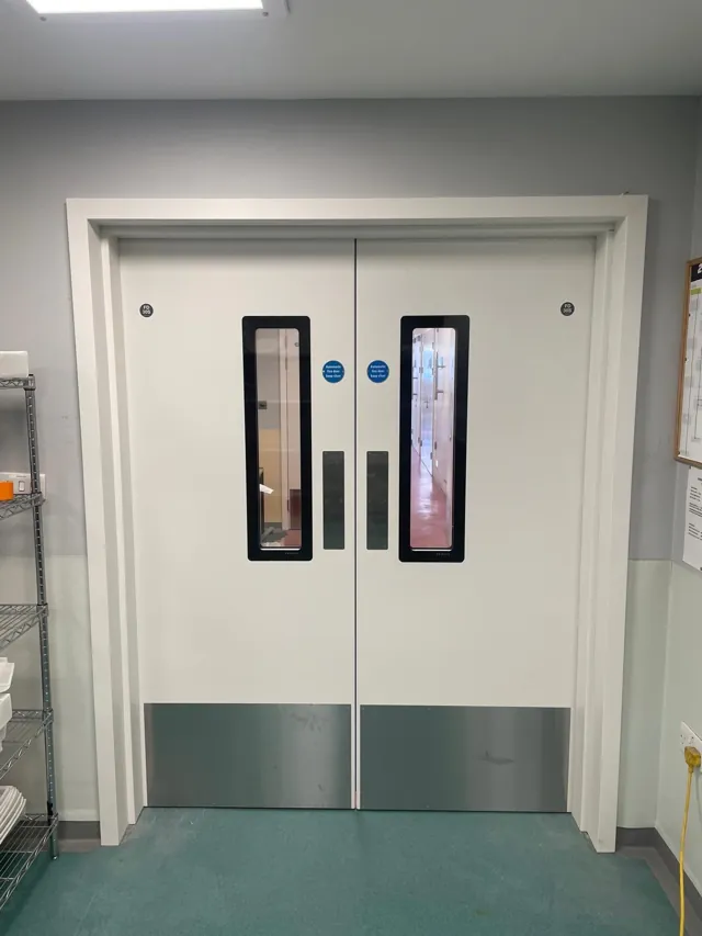 Front view of white double doors with green lower panels and overhead closers