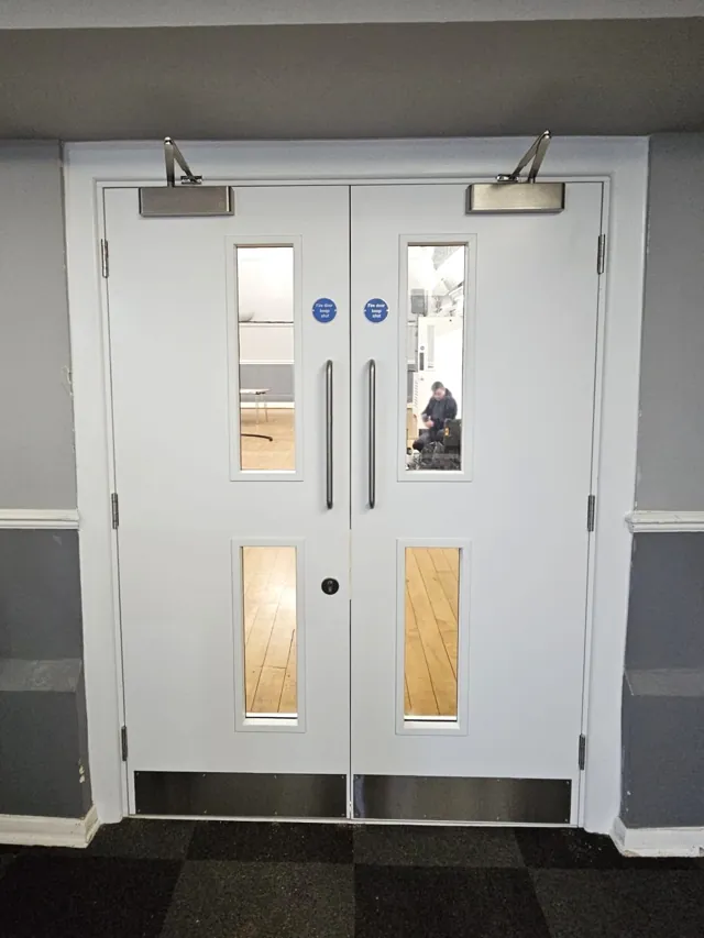 White double doors with vertical vision panels and overhead closers