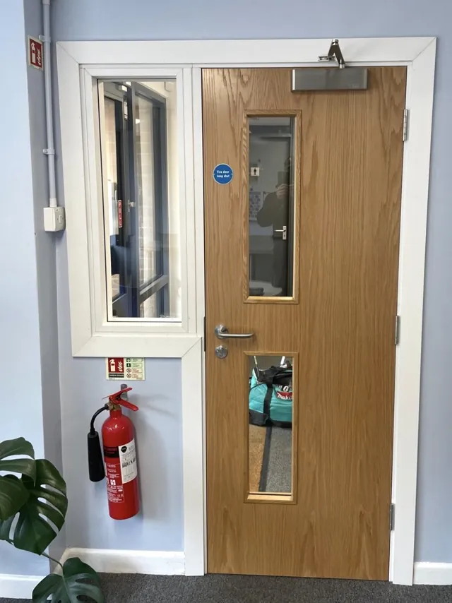 Oak-finish single door with two vision panels and adjacent glazing