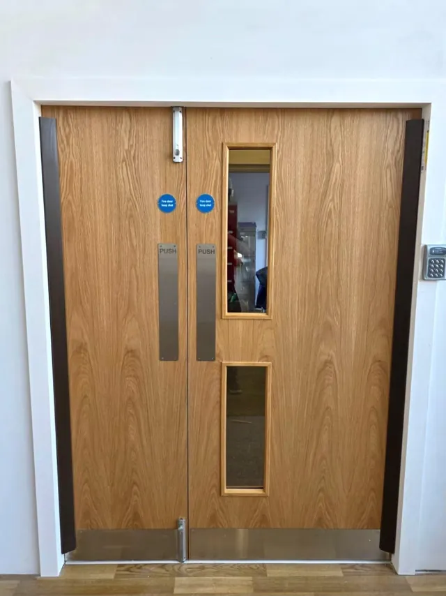 Oak-finish double doors with vertical glazing inside a white frame
