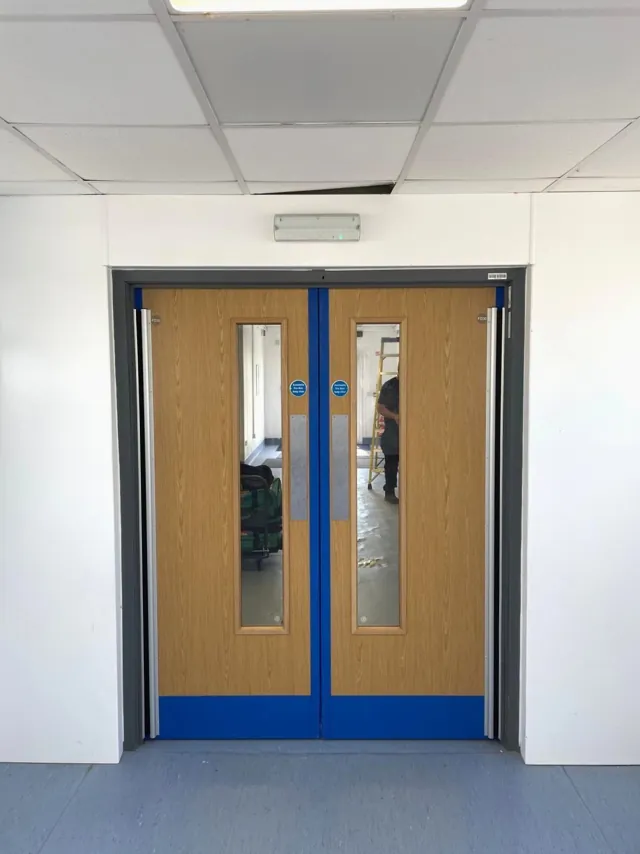 Timber double doors with vision panels and blue lower protection panels