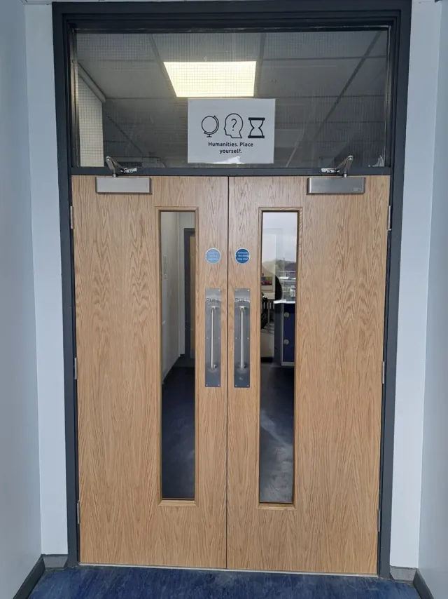 Timber double doors with long glazed panels and a dark-framed glazed overlight