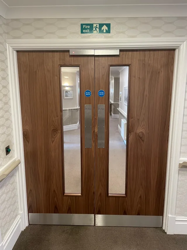 Timber double doors with long vision panels and a white surrounding frame